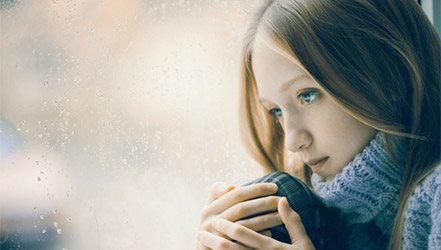 Грустная девушка с нехваткой витаминов возле окна осенью